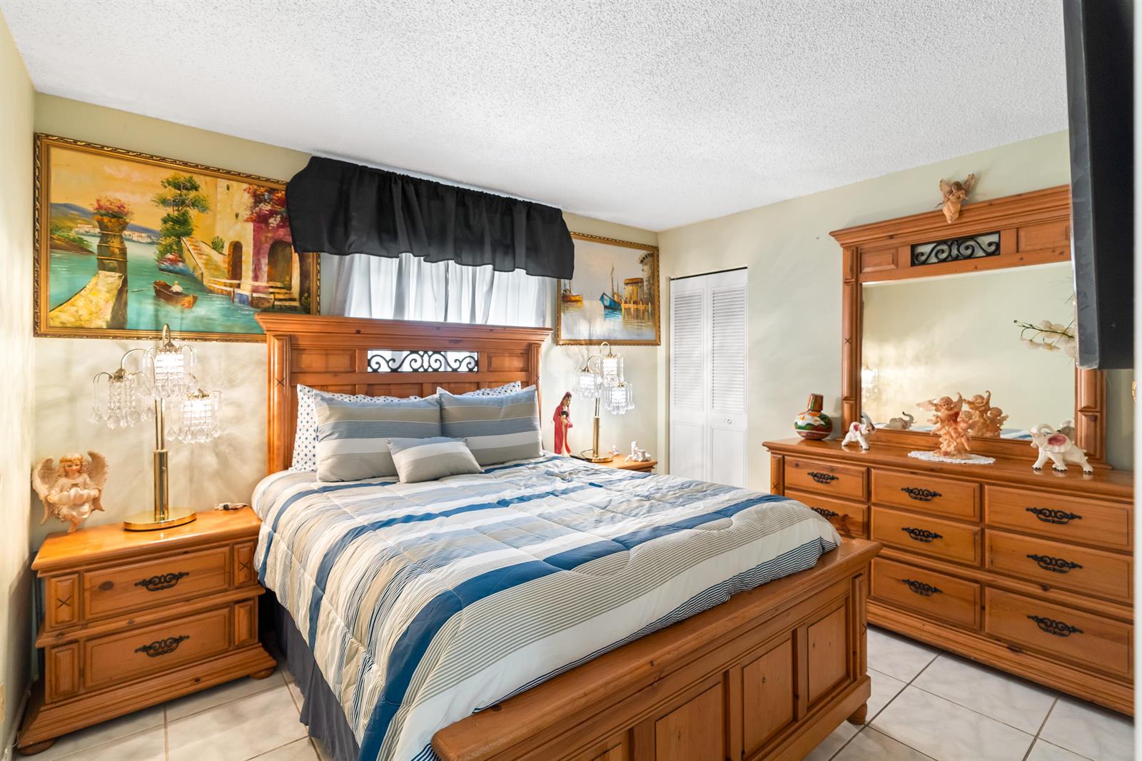 A bedroom features a wooden bed frame, matching dresser with mirror, and blue striped bedding — 4996 Sable Pine Circle # A1, West Palm Beach FL 33417, WEST PALM BEACH, FL