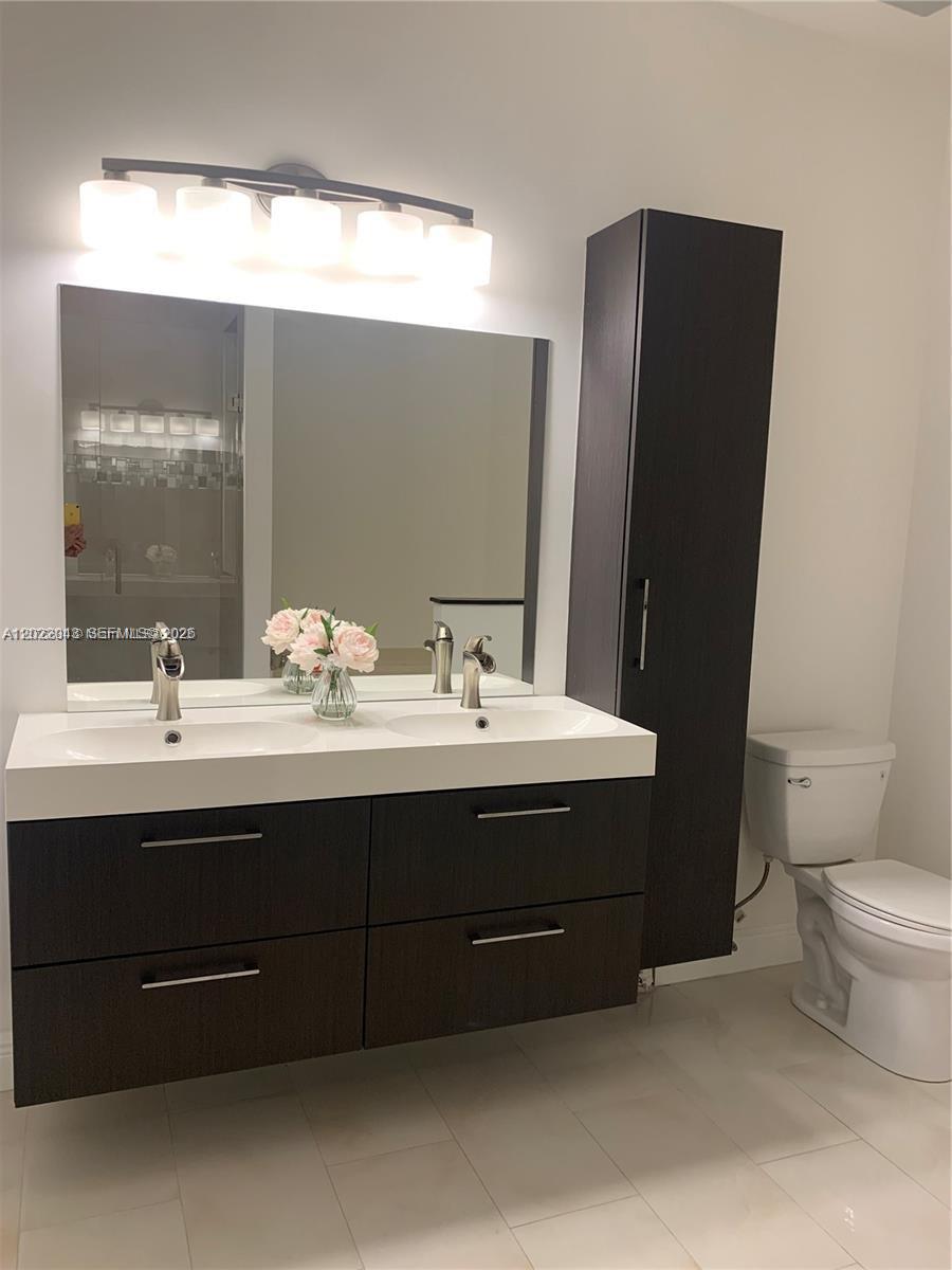 A modern bathroom features a double-sink vanity with dark wood cabinets and a tall storage tower — 649 NE 33rd Ter # 649, Homestead FL 33033, HOMESTEAD, FL