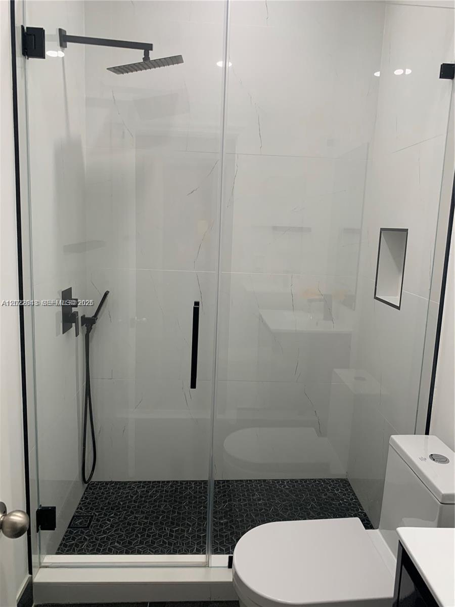 A modern bathroom features a glass-enclosed walk-in shower with black fixtures and tiled walls — 649 NE 33rd Ter # 649, Homestead FL 33033, HOMESTEAD, FL