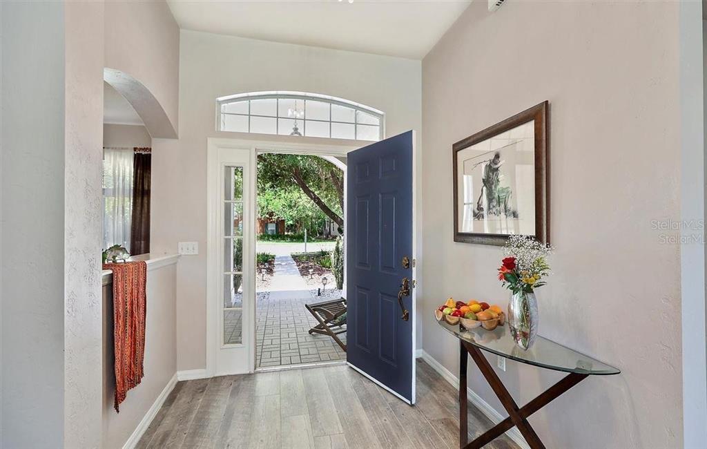 An entryway features a blue front door, wood-look flooring, and a glass-topped console table — 4009 NW 67TH PLACE, GAINESVILLE, FL