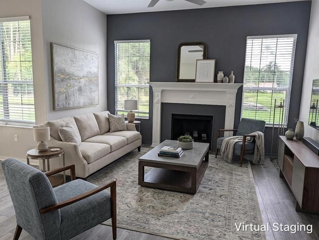 A living room with a fireplace, gray accent wall, beige sofa, and two blue armchairs — 4009 NW 67TH PLACE, GAINESVILLE, FL