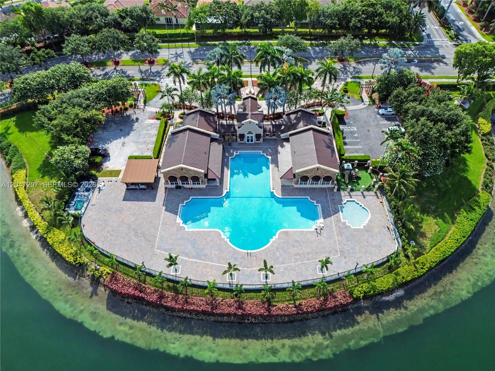 An aerial view shows a community pool complex with a clubhouse surrounded by a lake — 1555 NE 33rd Rd # 2, Homestead FL 33033, HOMESTEAD, FL