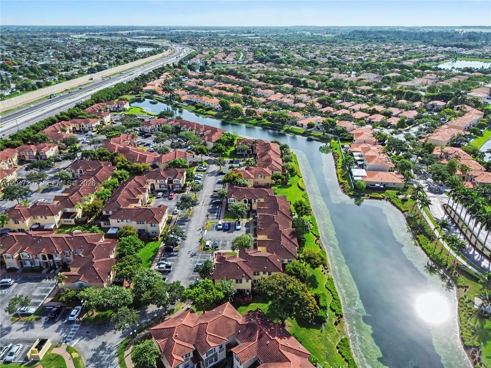 An aerial view shows a residential complex with red-tiled roofs beside a long canal — 1555 NE 33rd Rd # 2, Homestead FL 33033, HOMESTEAD, FL