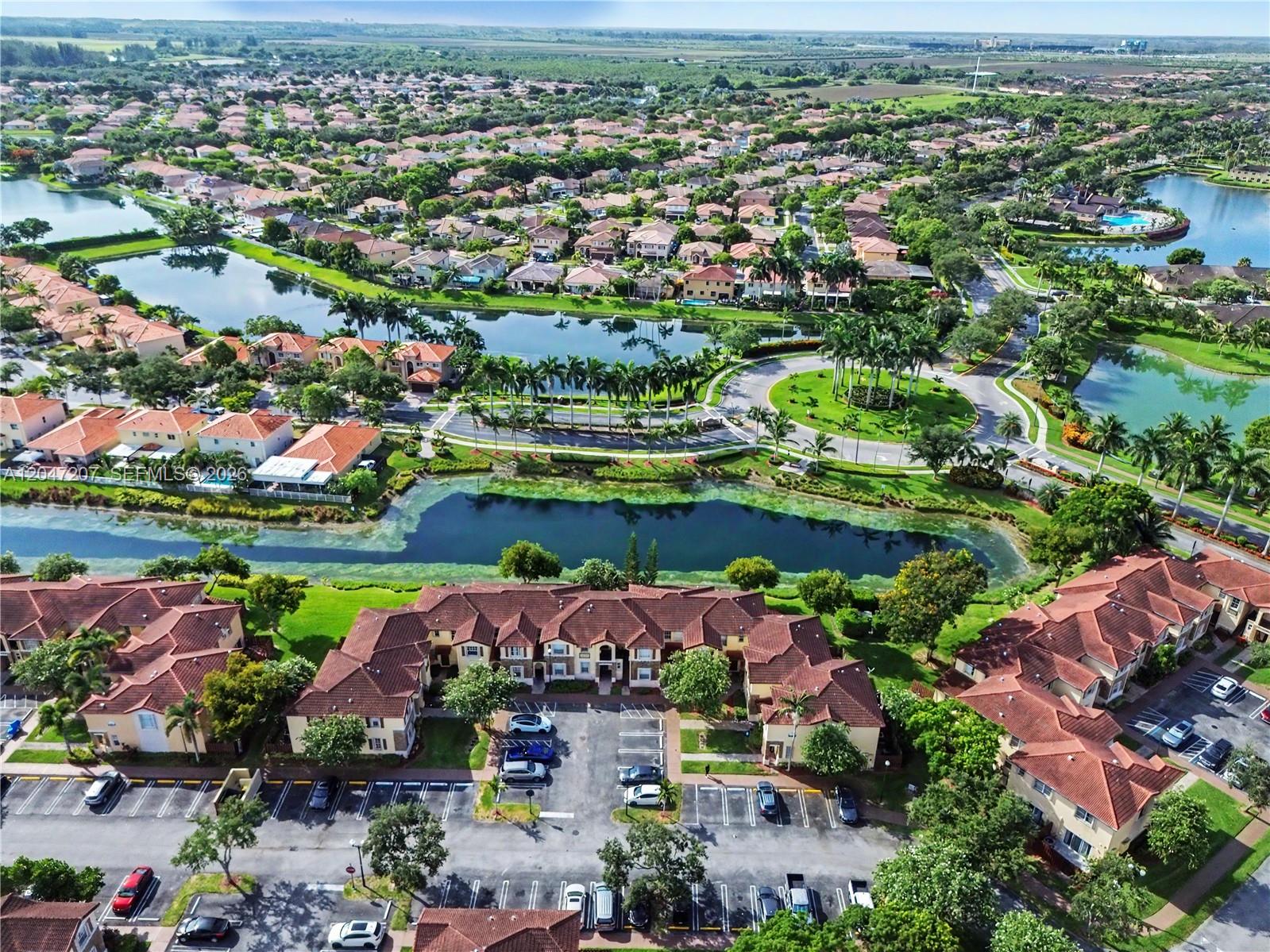 An aerial view shows a residential community with multi-family buildings, parking lots, and lakes — 1555 NE 33rd Rd # 2, Homestead FL 33033, HOMESTEAD, FL
