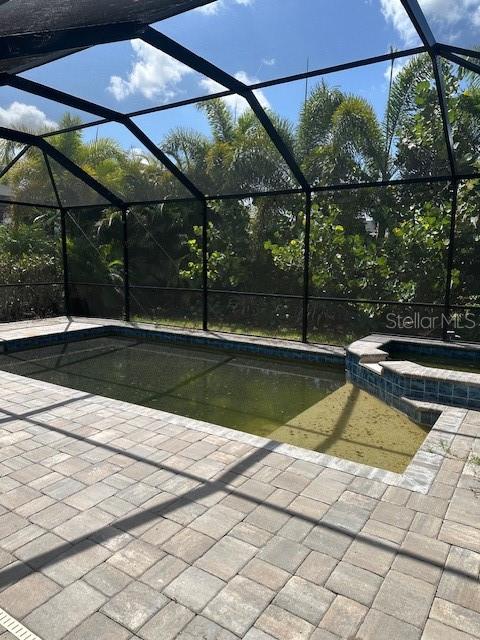 A screened-in swimming pool and spa with paver decking and surrounding tropical landscaping — 3360 CHESTERTOWN LOOP, BRADENTON, FL