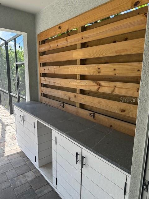 An outdoor kitchen area features white cabinets with a dark countertop and a wood-slatted backsplash — 3360 CHESTERTOWN LOOP, BRADENTON, FL