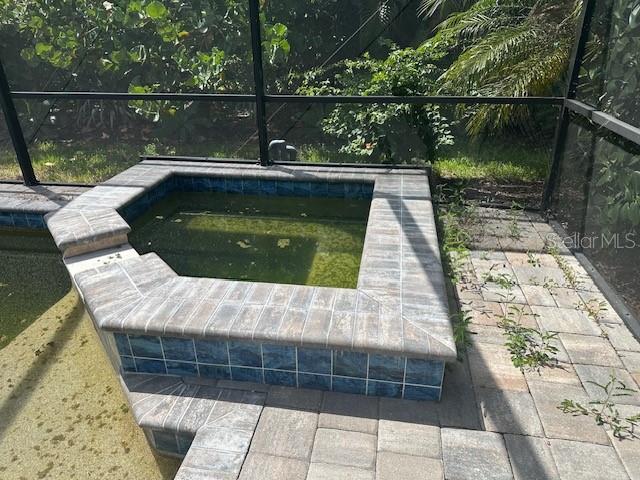 An elevated spa with blue tile sits next to a pool deck with stone pavers — 3360 CHESTERTOWN LOOP, BRADENTON, FL