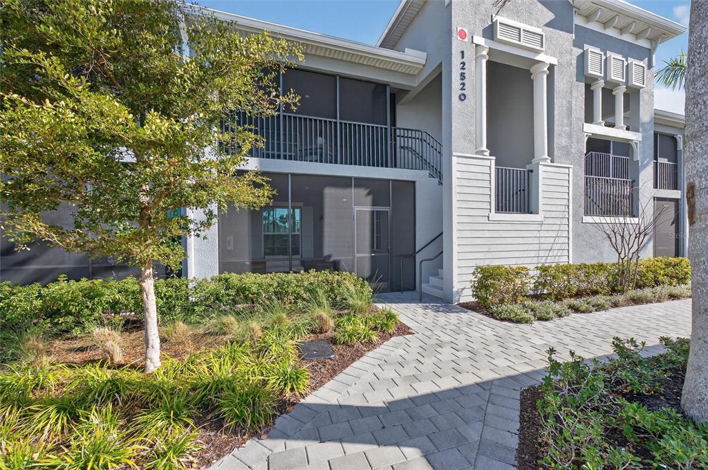 A two-story residential building features a screened-in ground floor patio and an upper balcony — 12520 GALAPAGOS COURT UNIT 105, VENICE, FL