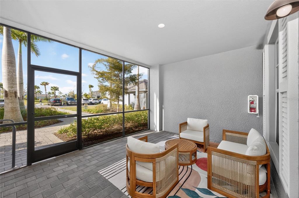 A screened-in patio features gray paver flooring, outdoor furniture, and a view of a parking lot — 12520 GALAPAGOS COURT UNIT 105, VENICE, FL