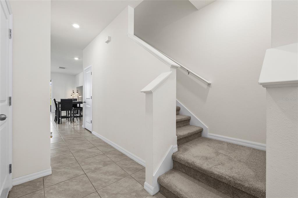 An interior view shows a tiled entryway leading to a dining area and carpeted stairs — 1287 COLT CREEK PLACE, WESLEY CHAPEL, FL