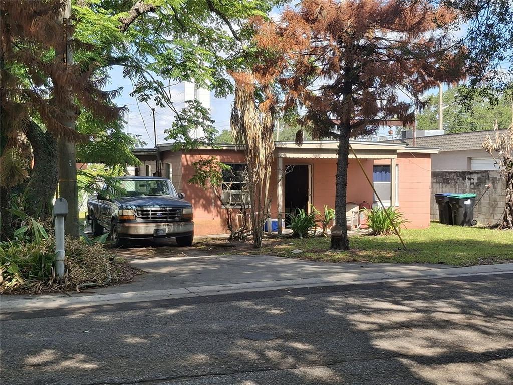 A single-story pink house with a front porch, a parked truck, and surrounding trees — 884 E MICHIGAN STREET, ORLANDO, FL