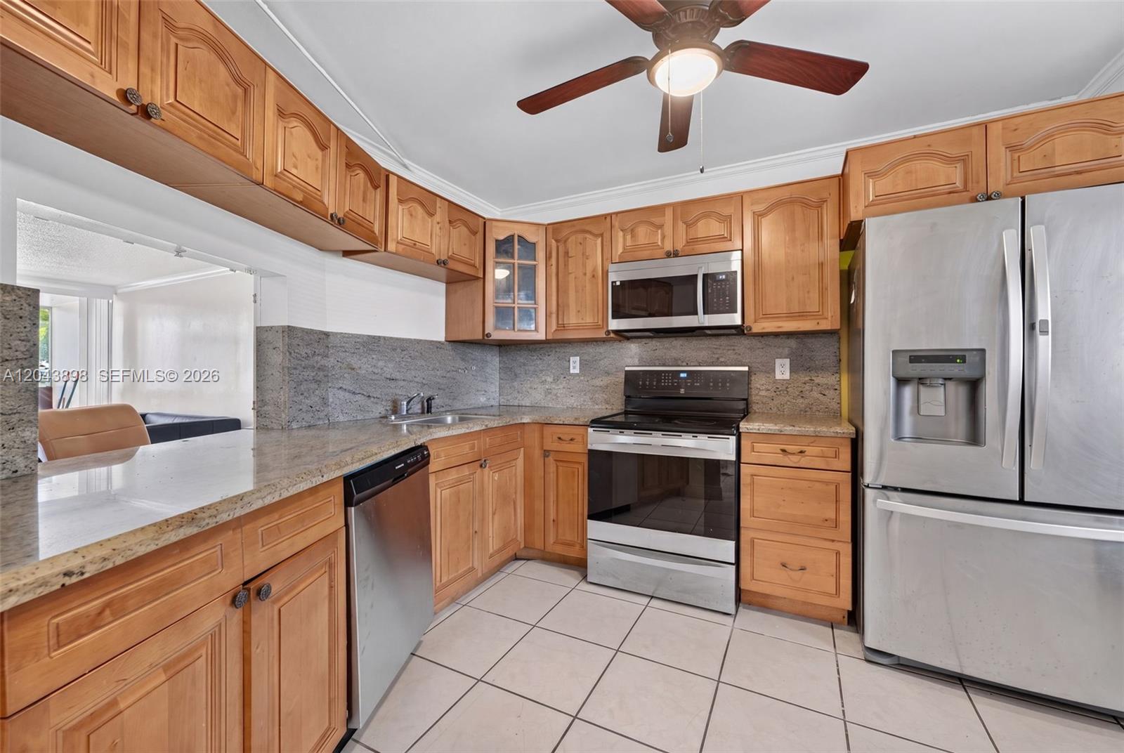 A kitchen features wooden cabinets, stainless steel appliances, granite countertops, and a ceiling fan — 1780 NE 191st St # 2, North Miami FL 33179, NORTH MIAMI, FL