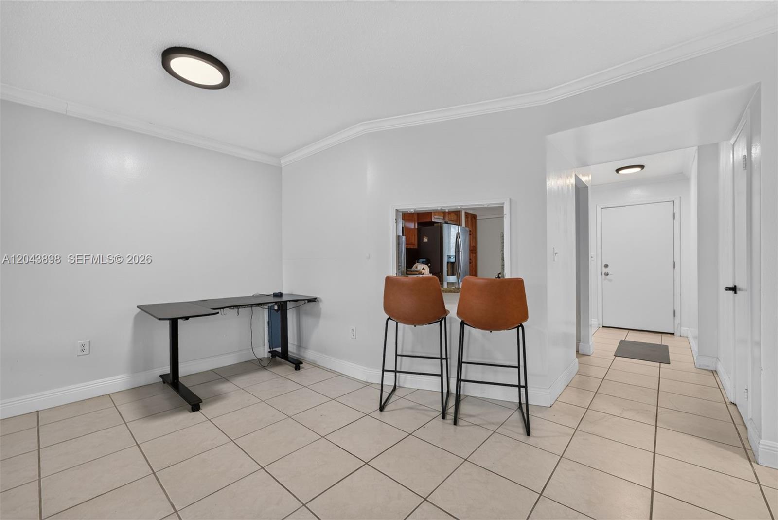 A room with light tile flooring features a black desk and two bar stools — 1780 NE 191st St # 2, North Miami FL 33179, NORTH MIAMI, FL