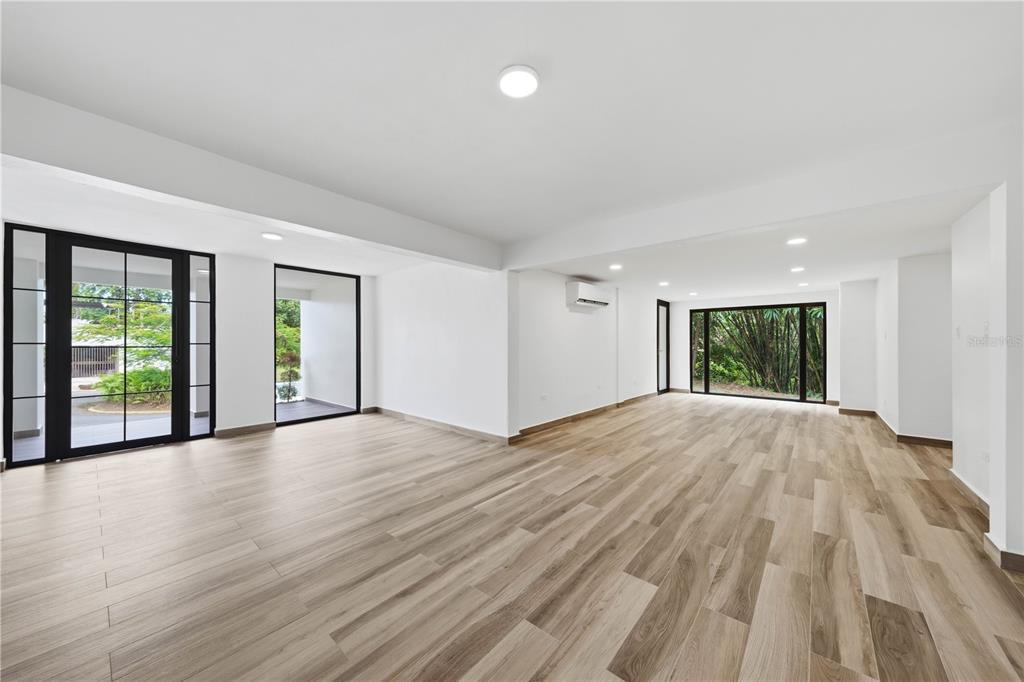 An empty room with light wood-look flooring, white walls, recessed lighting, and large glass doors — 15 SAN ISAAC STREET, SAN JUAN, PR