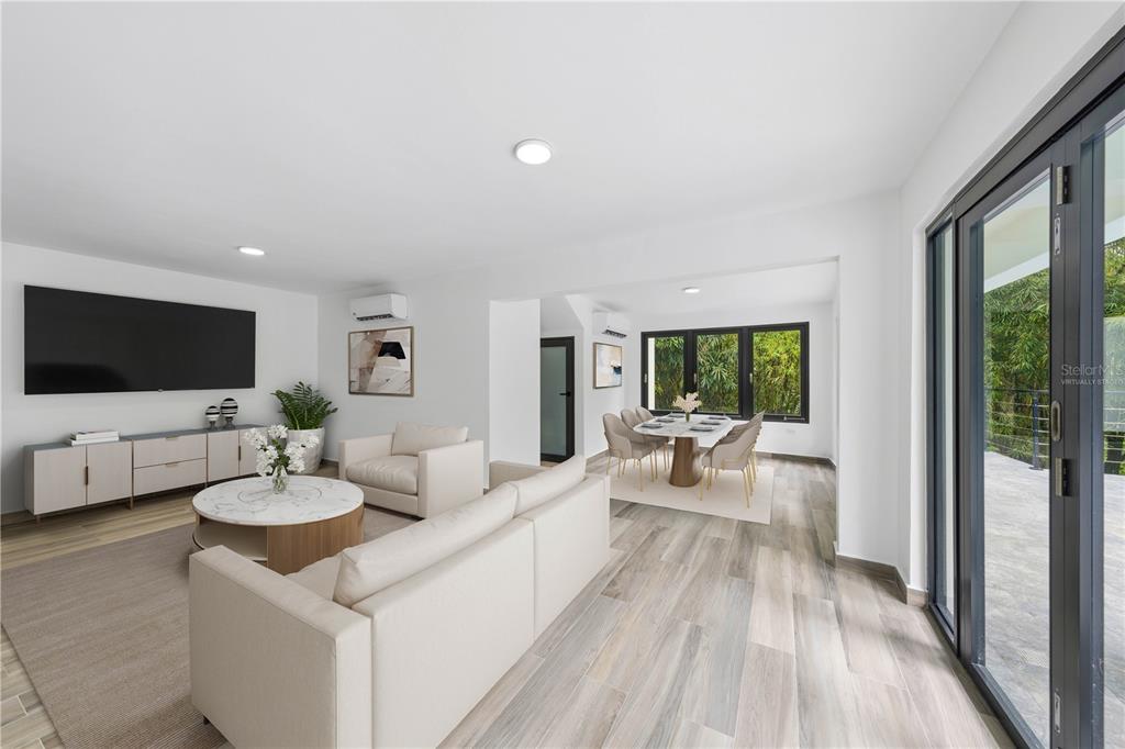 A modern living and dining area features light wood-look flooring, white walls, and glass doors — 15 SAN ISAAC STREET, SAN JUAN, PR