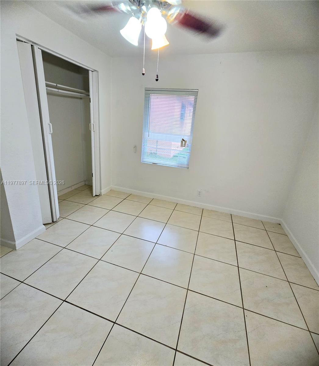 An empty bedroom features white walls, beige tile flooring, a ceiling fan, and a closet — 1436 NW 51st Ter, Miami FL 33142, MIAMI, FL