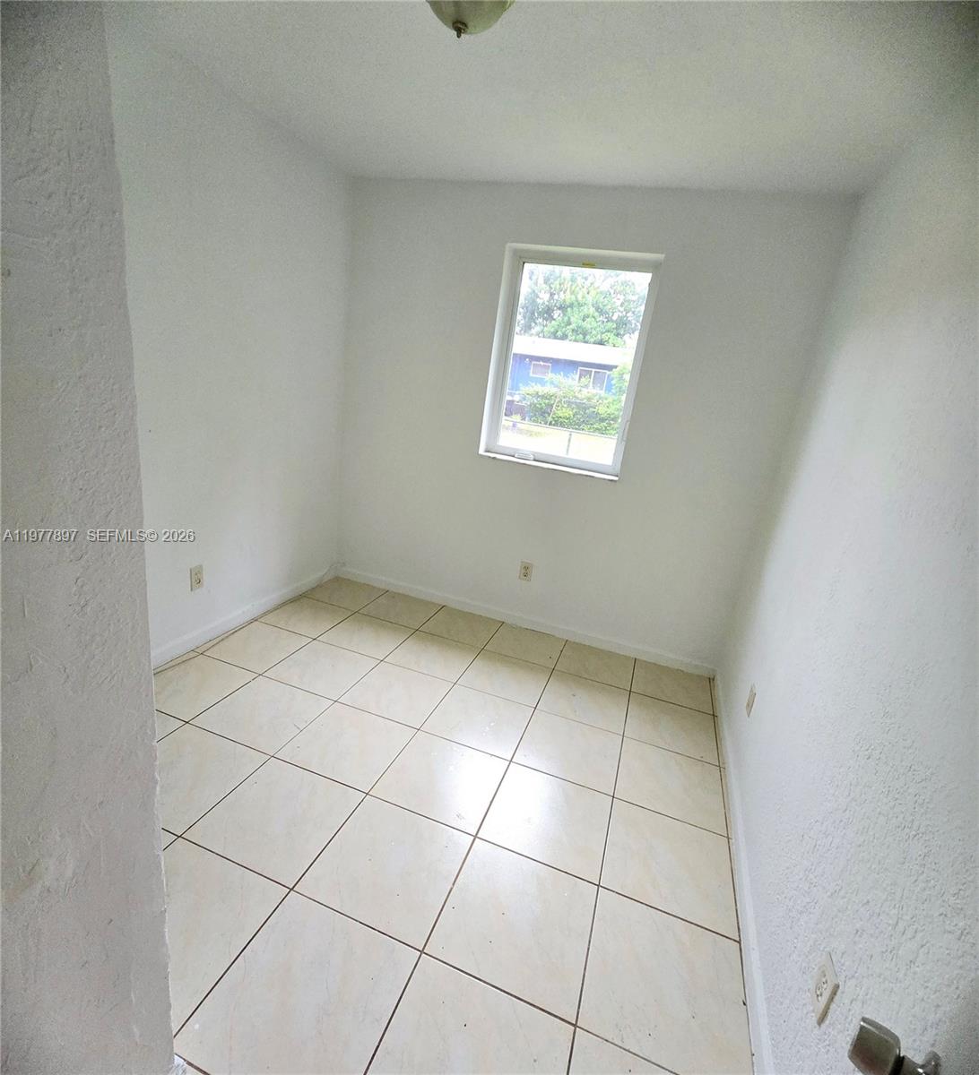 A small, empty room features white walls, a single window, and light-colored square floor tiles — 1436 NW 51st Ter, Miami FL 33142, MIAMI, FL