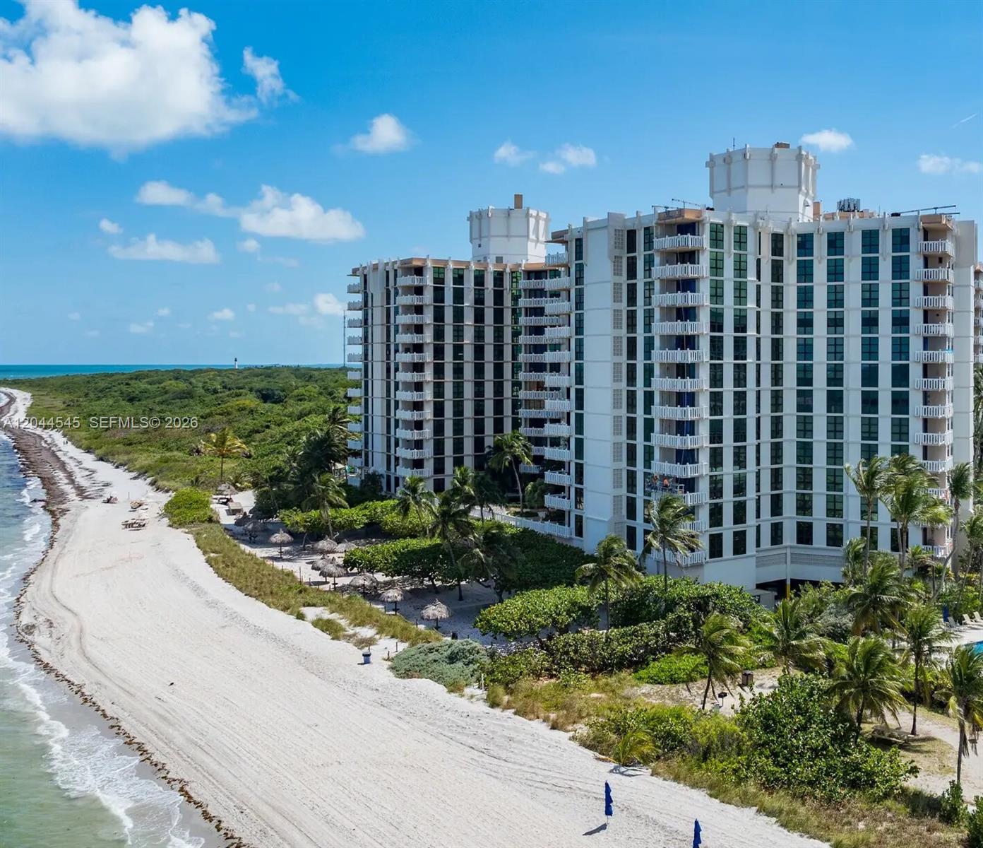 An aerial view shows a large white apartment building situated next to a sandy beach — 1111 Crandon Blvd # B705, Key Biscayne FL 33149, KEY BISCAYNE, FL