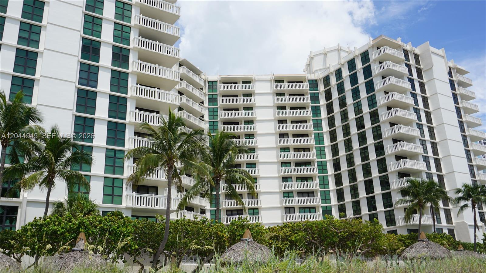 A multi-story white residential building features numerous balconies and large windows behind palm trees — 1111 Crandon Blvd # B705, Key Biscayne FL 33149, KEY BISCAYNE, FL