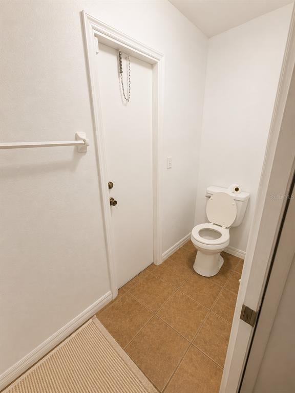 A small bathroom with tan tile flooring, white walls, and a white toilet — 2113 N NORMANDY BOULEVARD, DELTONA, FL