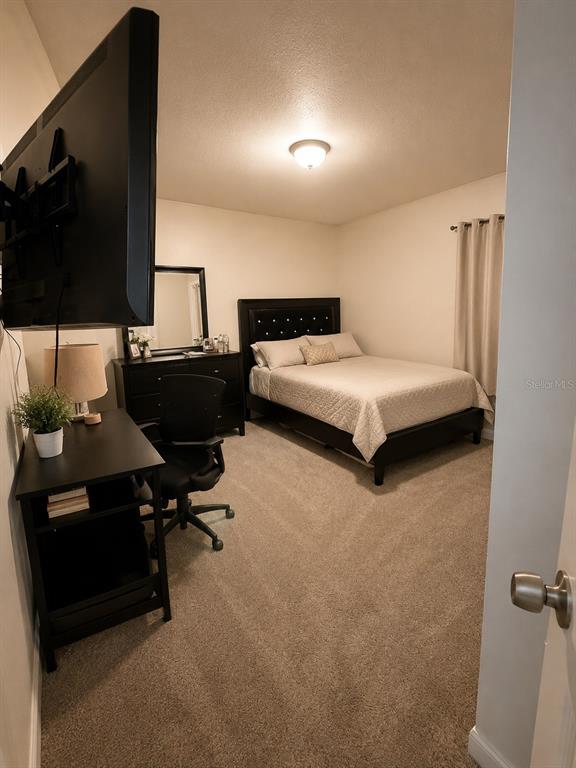 A bedroom features a bed with a dark headboard, a desk, and a television — 2113 N NORMANDY BOULEVARD, DELTONA, FL