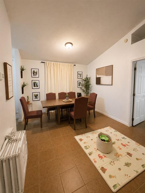 A dining room with a wooden table, six chairs, tiled floors, and a play mat — 2113 N NORMANDY BOULEVARD, DELTONA, FL