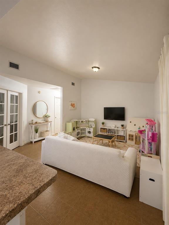 A living room features tile flooring, a white sofa, a television, and children's play equipment — 2113 N NORMANDY BOULEVARD, DELTONA, FL