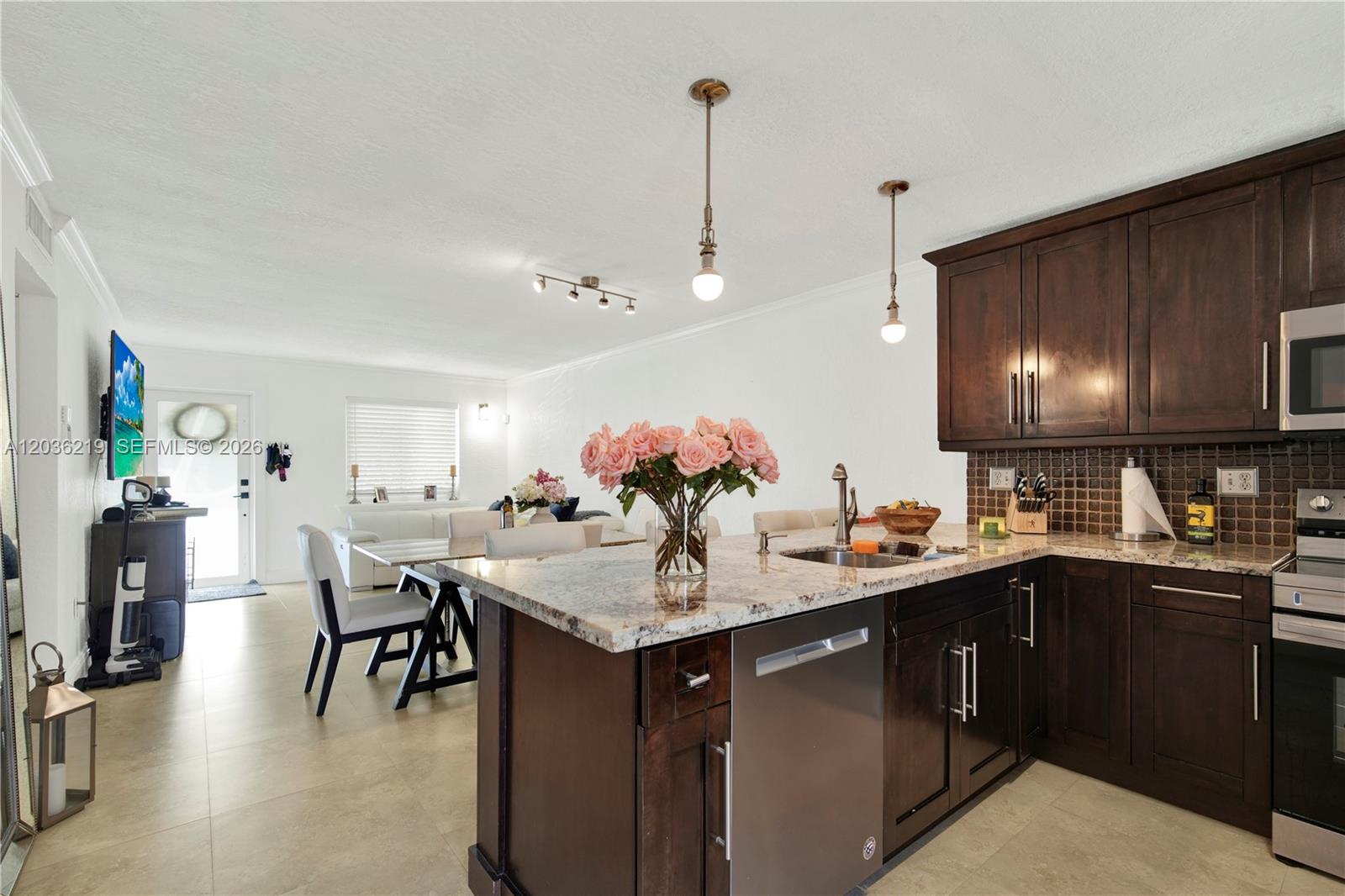A kitchen with dark wood cabinets and granite countertops opens into a dining area — 4260 SW 68th Ct, Miami FL 33155, MIAMI, FL