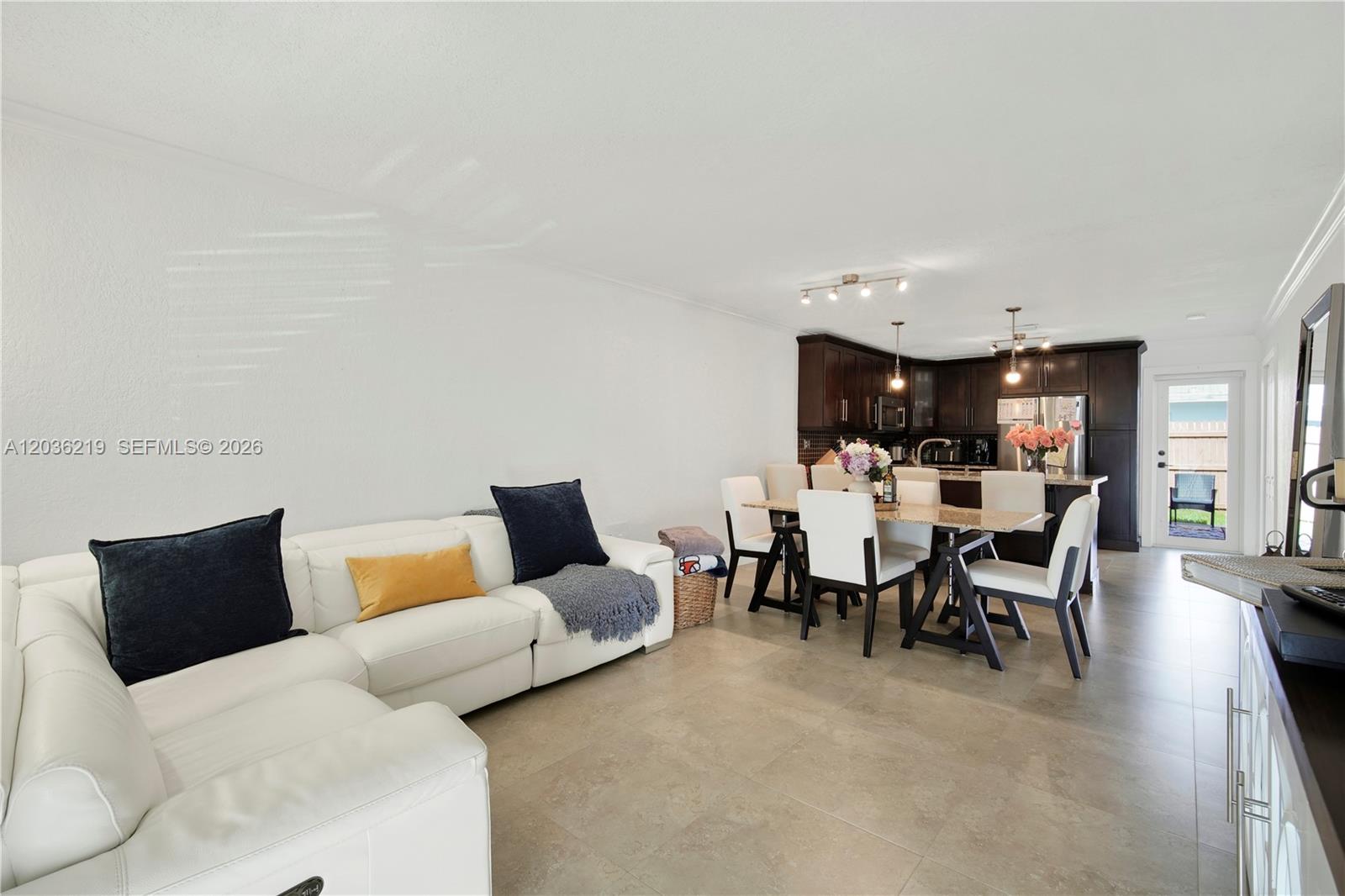 A white sofa sits in a living room adjacent to a dining area and kitchen — 4260 SW 68th Ct, Miami FL 33155, MIAMI, FL