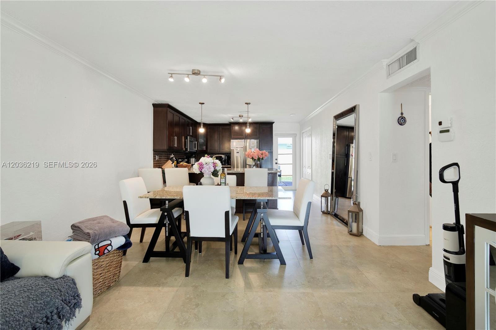 A dining area with a stone-topped table and white chairs sits before a dark-cabinet kitchen — 4260 SW 68th Ct, Miami FL 33155, MIAMI, FL