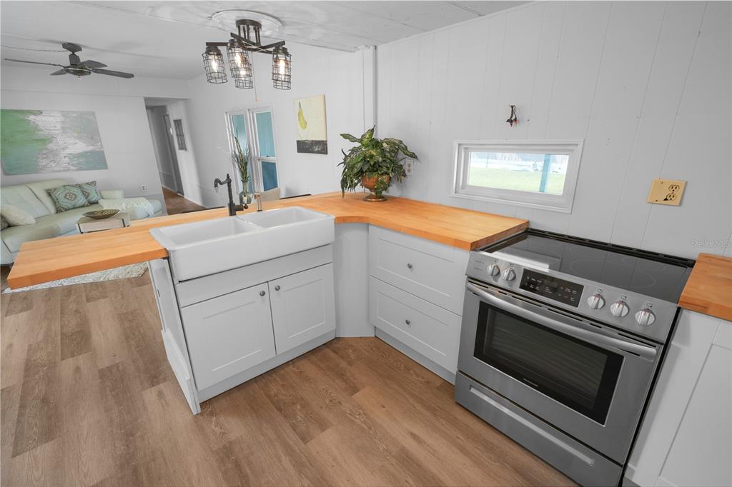A kitchen features a white farmhouse sink, butcher block countertops, and stainless steel appliances — 10921 LONDON DRIVE, PORT RICHEY, FL