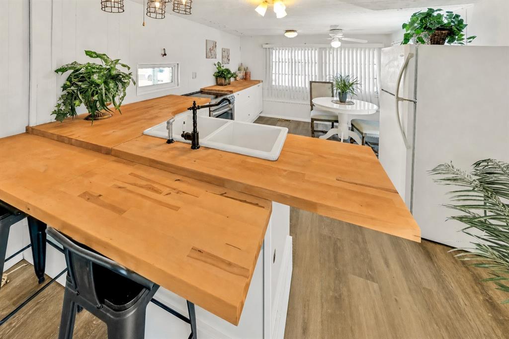 A kitchen features a wooden countertop island with a sink and white cabinetry — 10921 LONDON DRIVE, PORT RICHEY, FL