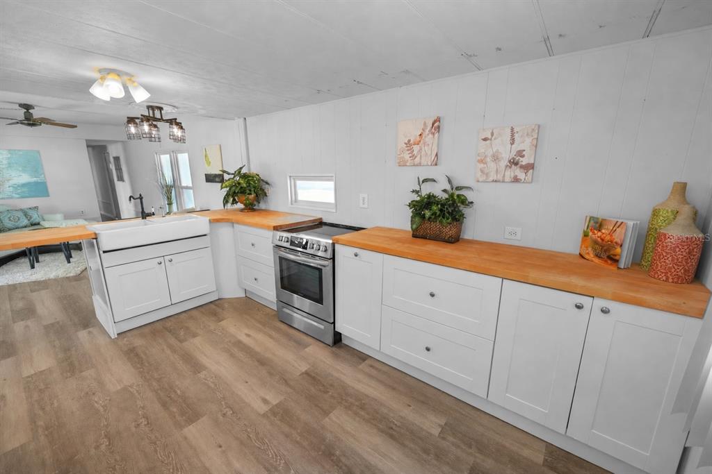 A kitchen features white cabinets, wood countertops, a farmhouse sink, and stainless steel appliances — 10921 LONDON DRIVE, PORT RICHEY, FL