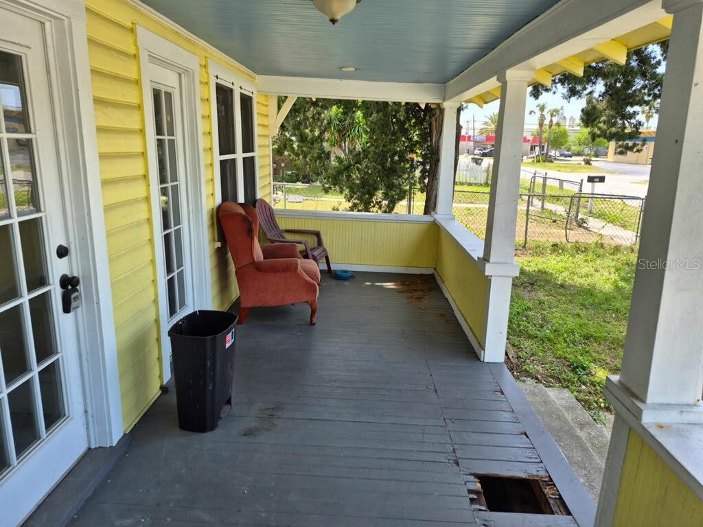 A yellow-sided house has a covered porch with a gray wooden floor and a hole — 219 NORTH STREET, DAYTONA BEACH, FL