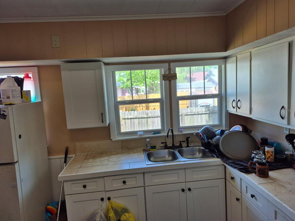 A kitchen features white cabinets, a tiled countertop, a double sink, and a window — 219 NORTH STREET, DAYTONA BEACH, FL
