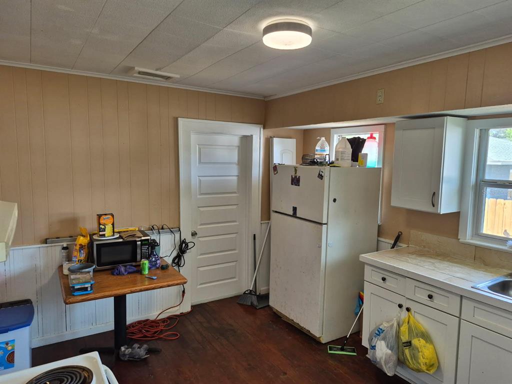 A kitchen with wood-paneled walls, white cabinets, a refrigerator, and a small wooden table — 219 NORTH STREET, DAYTONA BEACH, FL