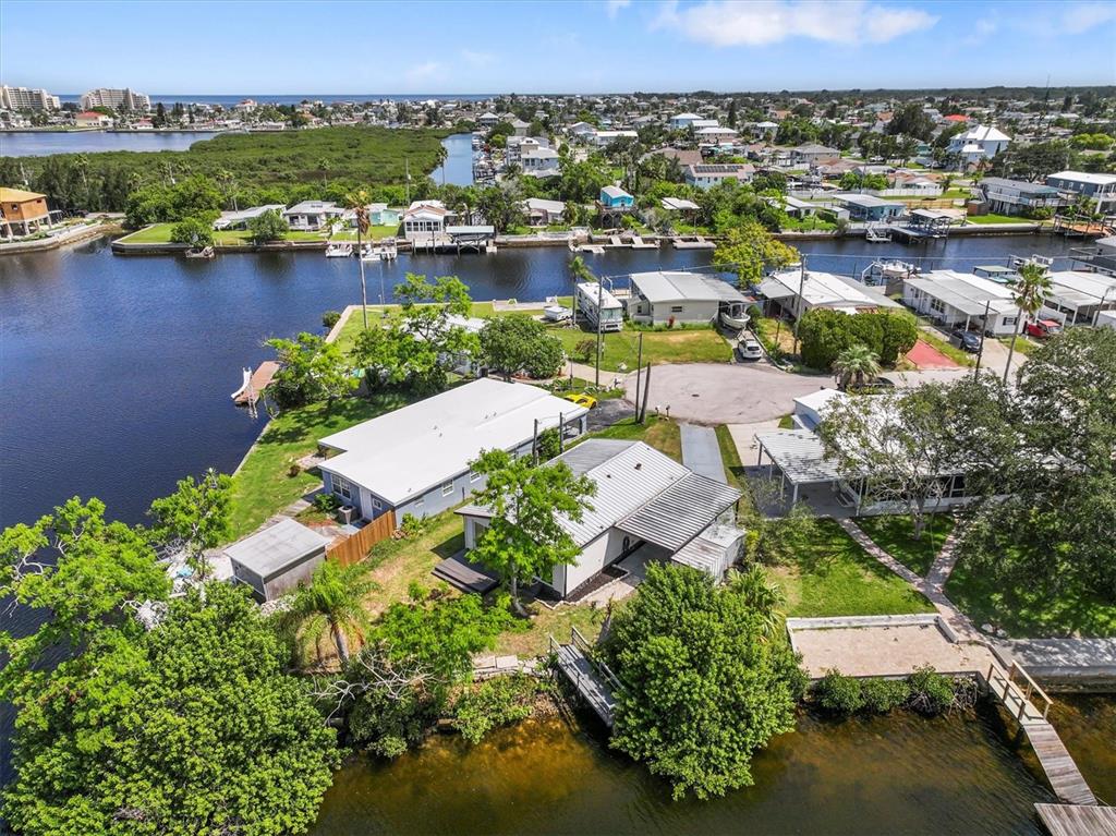 An aerial view shows waterfront homes with docks, lush vegetation, and a canal in Florida — 13147 CABIN COURT, HUDSON, FL