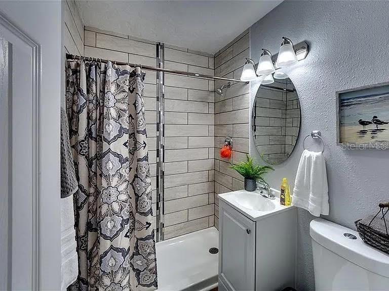 A bathroom features a tiled shower stall, a vanity with a mirror, and a toilet — 120 AVENIDA DE BAHA, NOKOMIS, FL