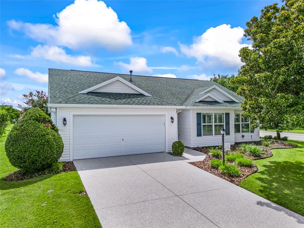 A white single-story house with a green shingled roof and a two-car garage — 17899 SE 87TH BOURNE AVENUE, THE VILLAGES, FL