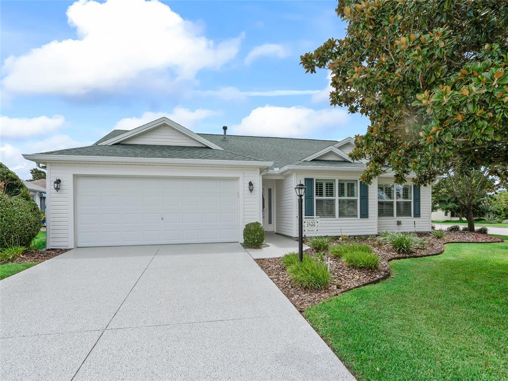 A single-story house with white siding, a green roof, and a concrete driveway — 17899 SE 87TH BOURNE AVENUE, THE VILLAGES, FL