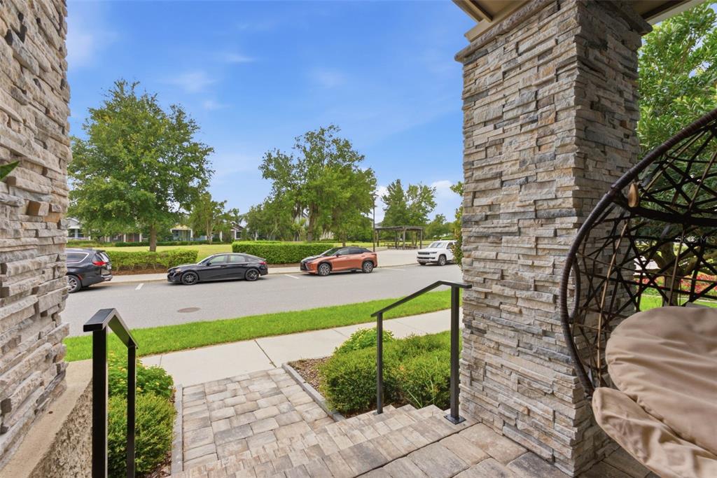 A stone-columned porch overlooks a street with parked cars and a green park area — 6921 ARNOLDSON STREET, ORLANDO, FL