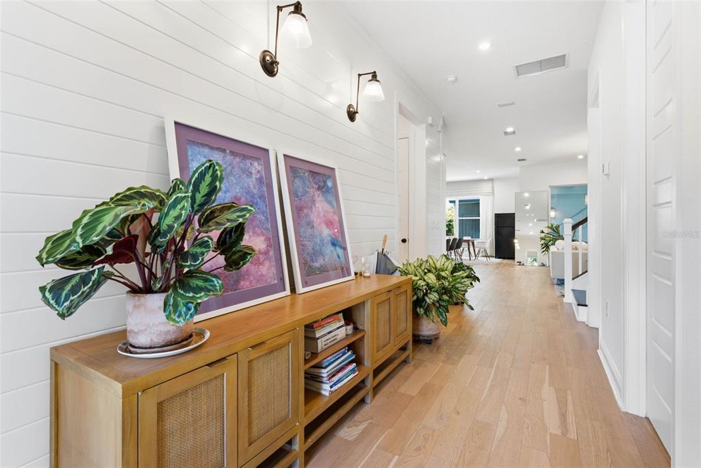 A hallway features white shiplap walls, a wooden console table with decor, and light wood flooring — 6921 ARNOLDSON STREET, ORLANDO, FL