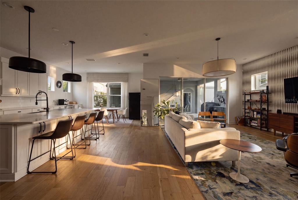 An open-concept kitchen and living area features white cabinetry, a large island, and hardwood floors — 6921 ARNOLDSON STREET, ORLANDO, FL