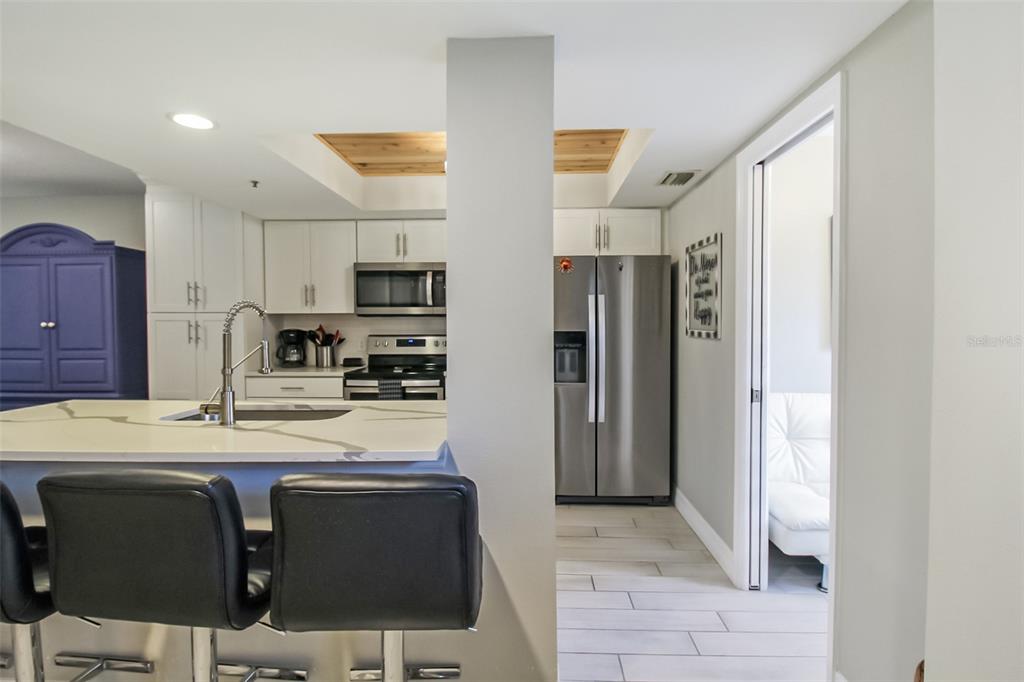 A kitchen features white cabinets, stainless steel appliances, a quartz island, and wood-paneled ceiling accents — 1313 SIESTA BAYSIDE DRIVE UNIT 1313-D, SARASOTA, FL