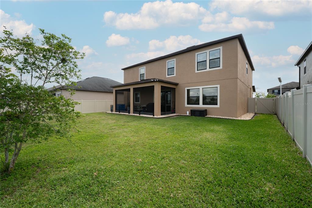 A grassy bank overlooks a retention pond surrounded by suburban houses under a cloudy sky — 8099 LAGO MIST WAY, WESLEY CHAPEL, FL
