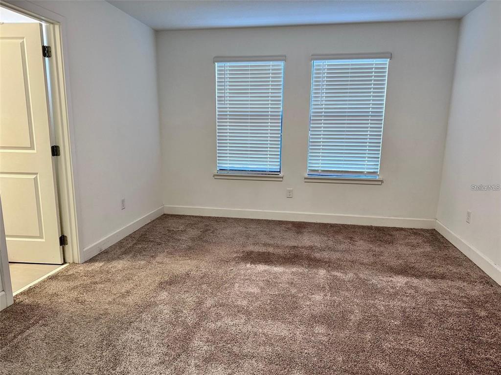 An empty bedroom features white walls, brown carpet, and two windows with closed blinds — 4774 TERRA ESMERALDA DRIVE, KISSIMMEE, FL