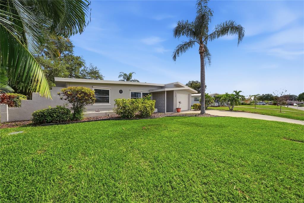 A single-story house with a flat roof, gray exterior, and a palm tree in front — 14190 PAGE AVENUE, LARGO, FL