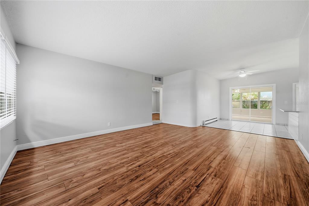 An empty room with wood-look flooring, white walls, and a sliding glass door — 14190 PAGE AVENUE, LARGO, FL