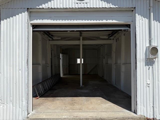 An open, empty metal-sided garage features a concrete floor and a single support post — 323 N DELAWARE AVENUE UNIT 3, DELAND, FL