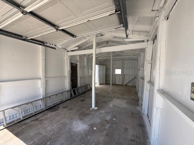 An interior view of a detached garage with exposed framing, white walls, and a concrete floor — 323 N DELAWARE AVENUE UNIT 3, DELAND, FL
